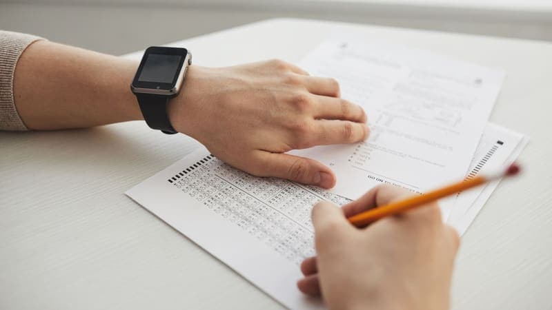 Close-up of hands filling in a multiple-choice answer sheet with a pencil