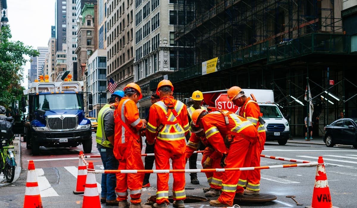 Construction crew in orange safety suits repairing a New York City street