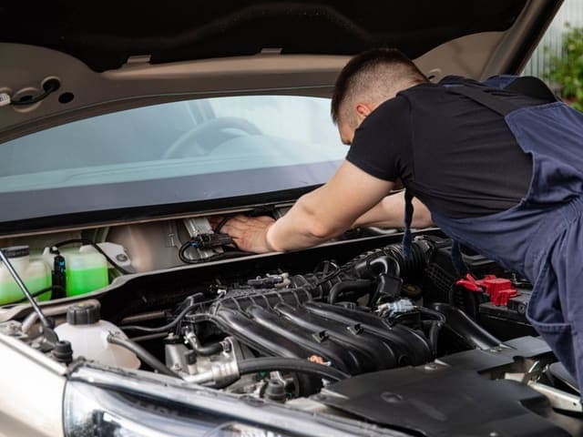 Automotive technician working in a car's engine bay