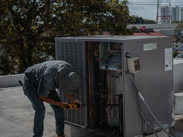 Technician servicing a rooftop air conditioning unit