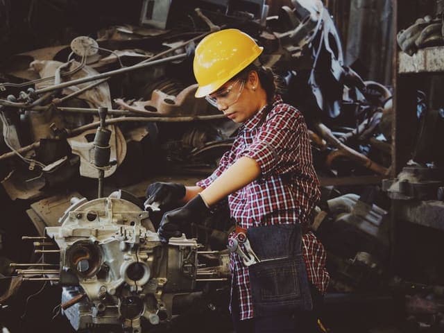 Industrial mechanic in a hard hat repairing machinery in a workshop